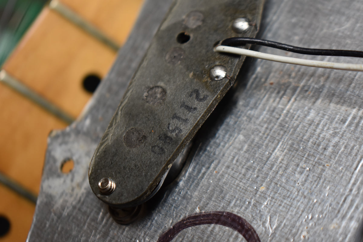Close-up of the underside of a dark gray pickup with white and black wires, showing a stamped number and wear on the metal baseplate.