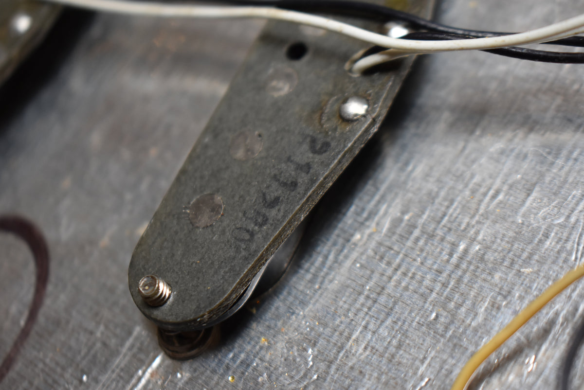Close-up of the underside of a pickup, showing a dark gray baseplate with visible solder joints, wires, and a stamped number.