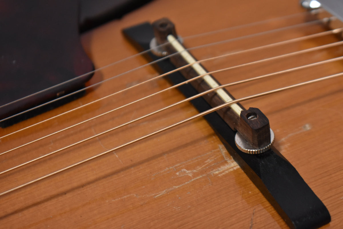 Close-up of the sunburst body and floating bridge with a bone saddle, showing heavy pick wear and finish checking.