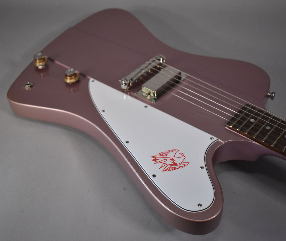 Close-up of a metallic heather poly Firebird body, showing the white pickguard with a red bird graphic and two gold knobs.