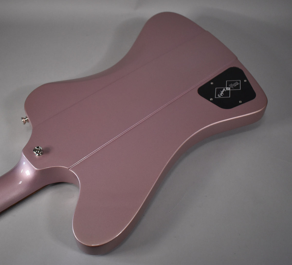 The back of a metallic heather poly Firebird guitar, showing the neck joint, strap button, and control cavity cover.
