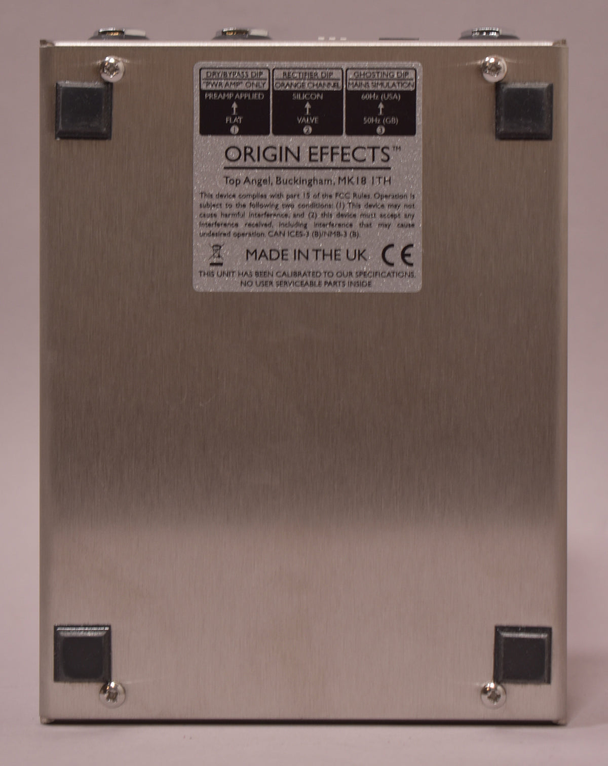The pedal's brushed silver bottom panel is shown, with four black rubber feet and a large rectangular info sticker.