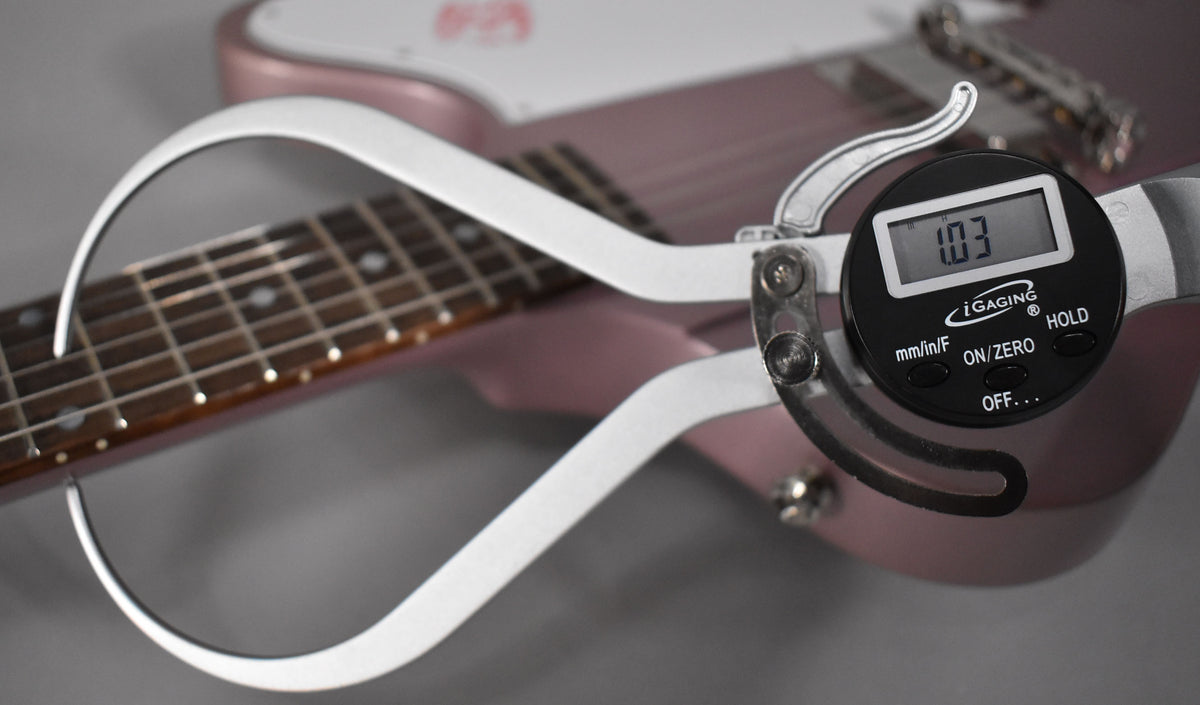 A digital caliper measures the string height at 1.03mm above the frets on the heather poly Firebird's rosewood fretboard.