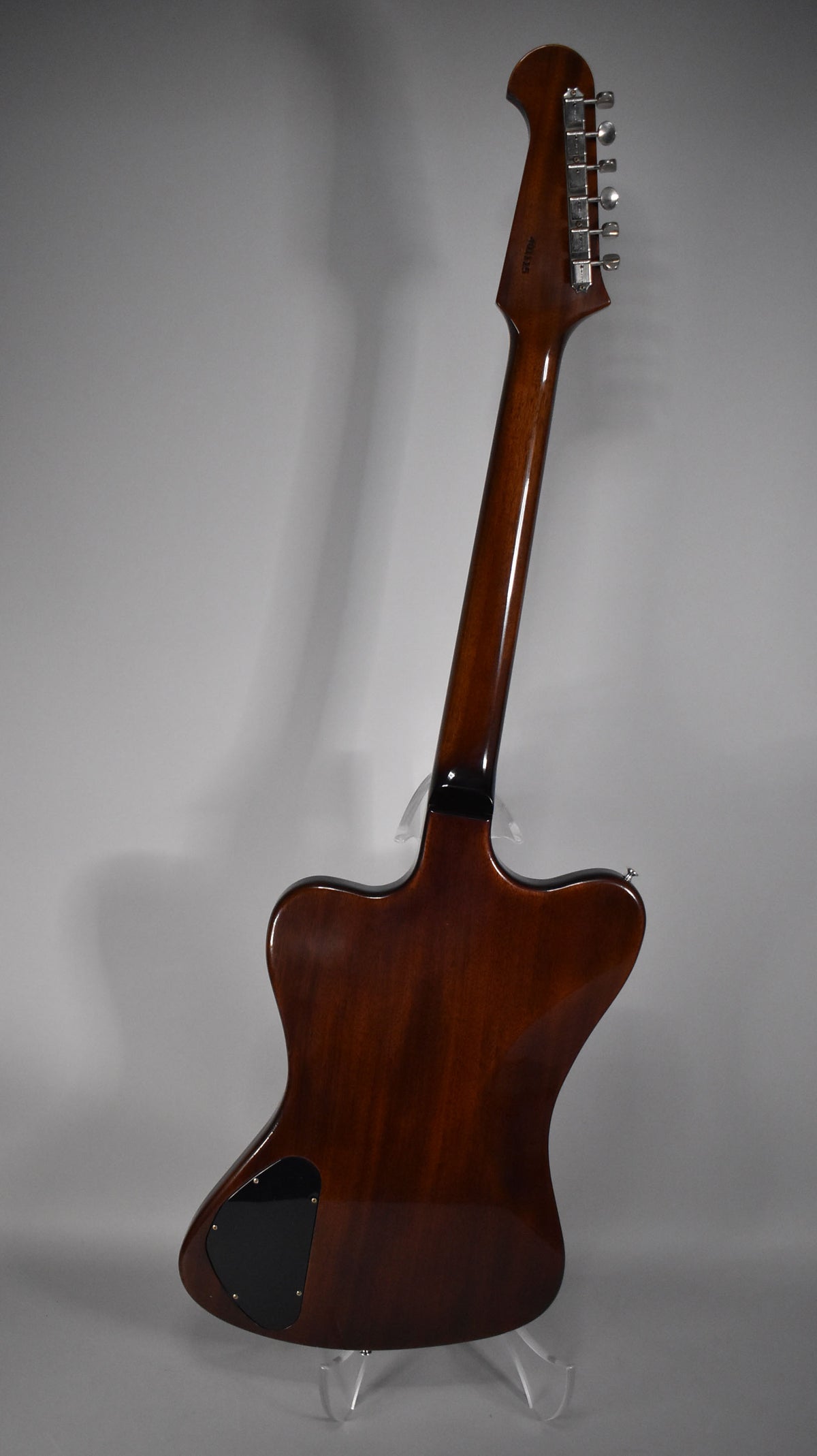 The guitar's dark sunburst back and neck are visible from a high angle, with six chrome tuners on the headstock and a black control plate.