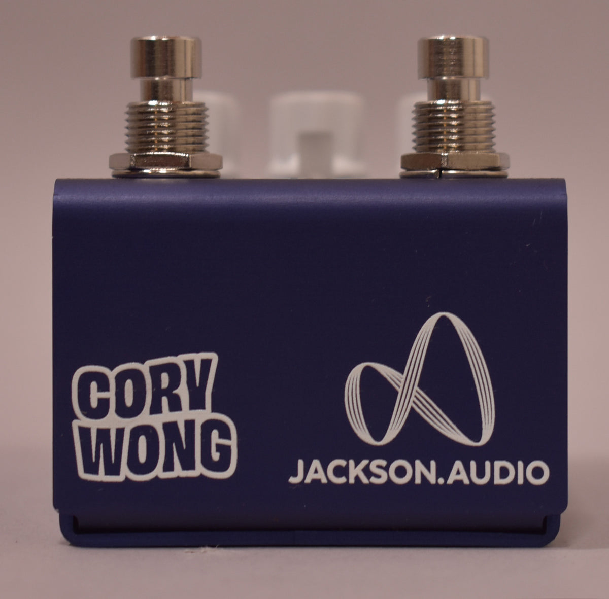 The dark blue pedal is viewed from the front, showing two silver footswitches and white lettering on the lower half.