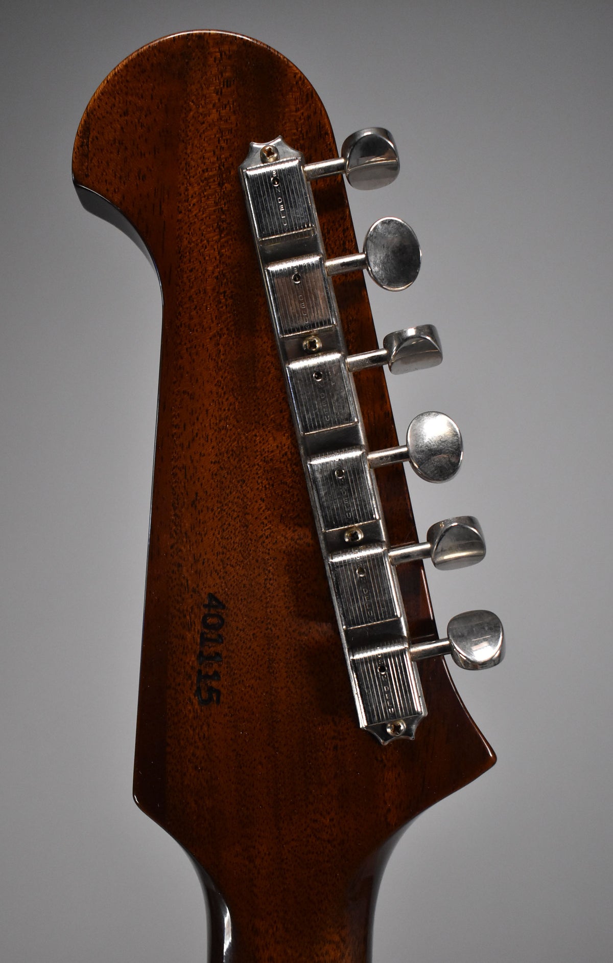 The back of the guitar's dark brown headstock, with six chrome tuners and a faint "401115" serial number near the neck joint.