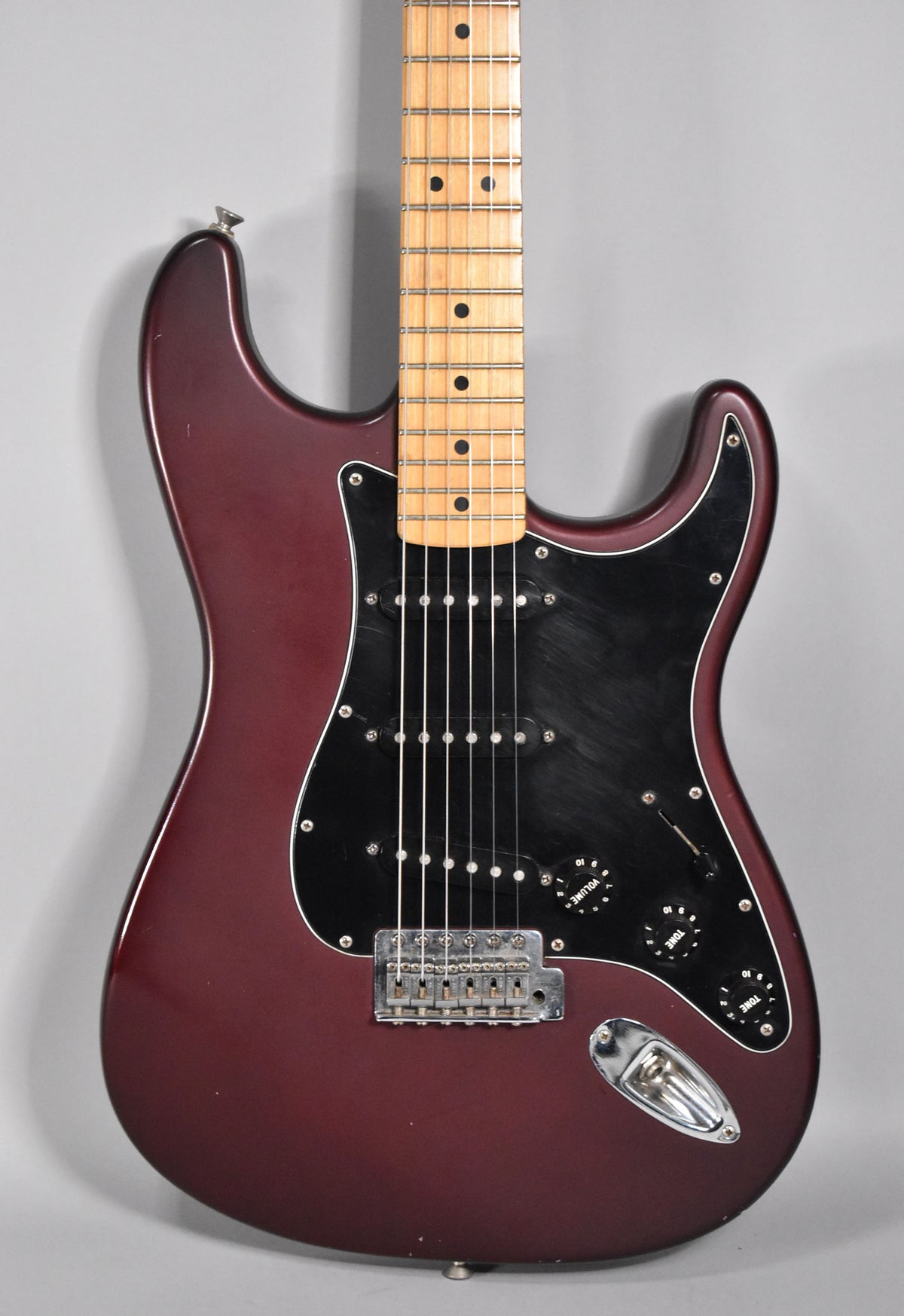 Full-frame view of a satin metallic red electric guitar with a maple neck, black pickguard, and chrome hardware.