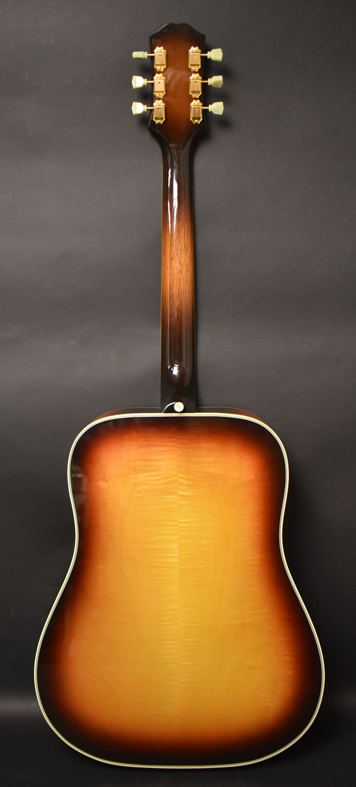 The guitar's back, neck, and headstock are visible, showing a sunburst finish with a lighter center and dark edges, and gold tuners.