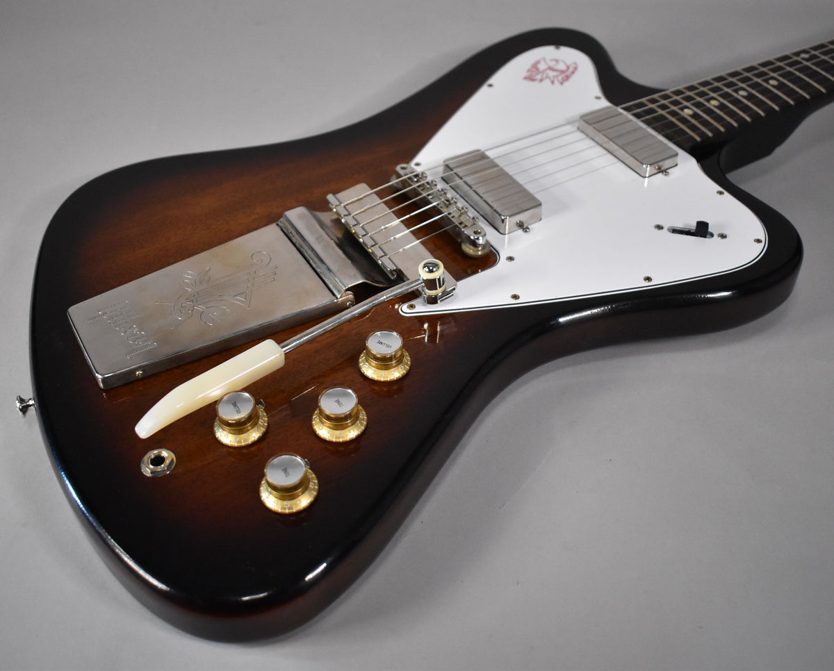 The guitar's body, in a glossy vintage sunburst, shows a white pickguard, two chrome pickups, and four gold control knobs.