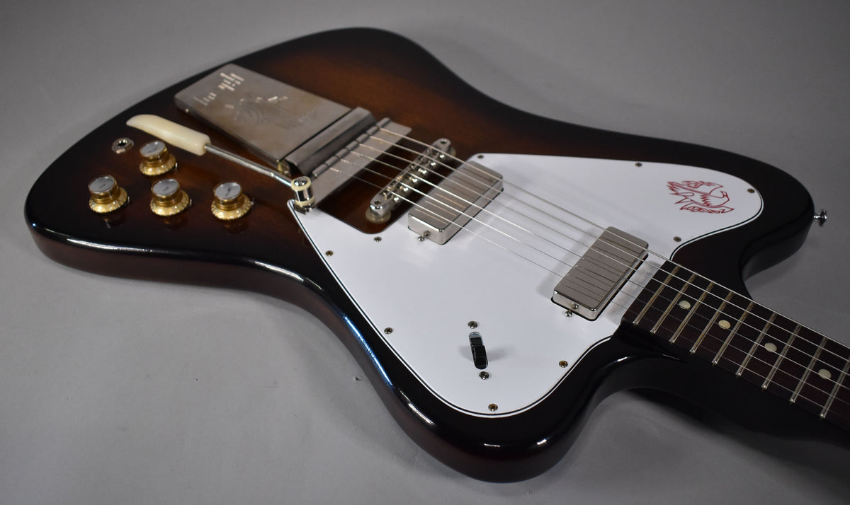 The Firebird's upper body, showing the vintage sunburst finish, white pickguard with red bird graphic, and vibrato tailpiece.