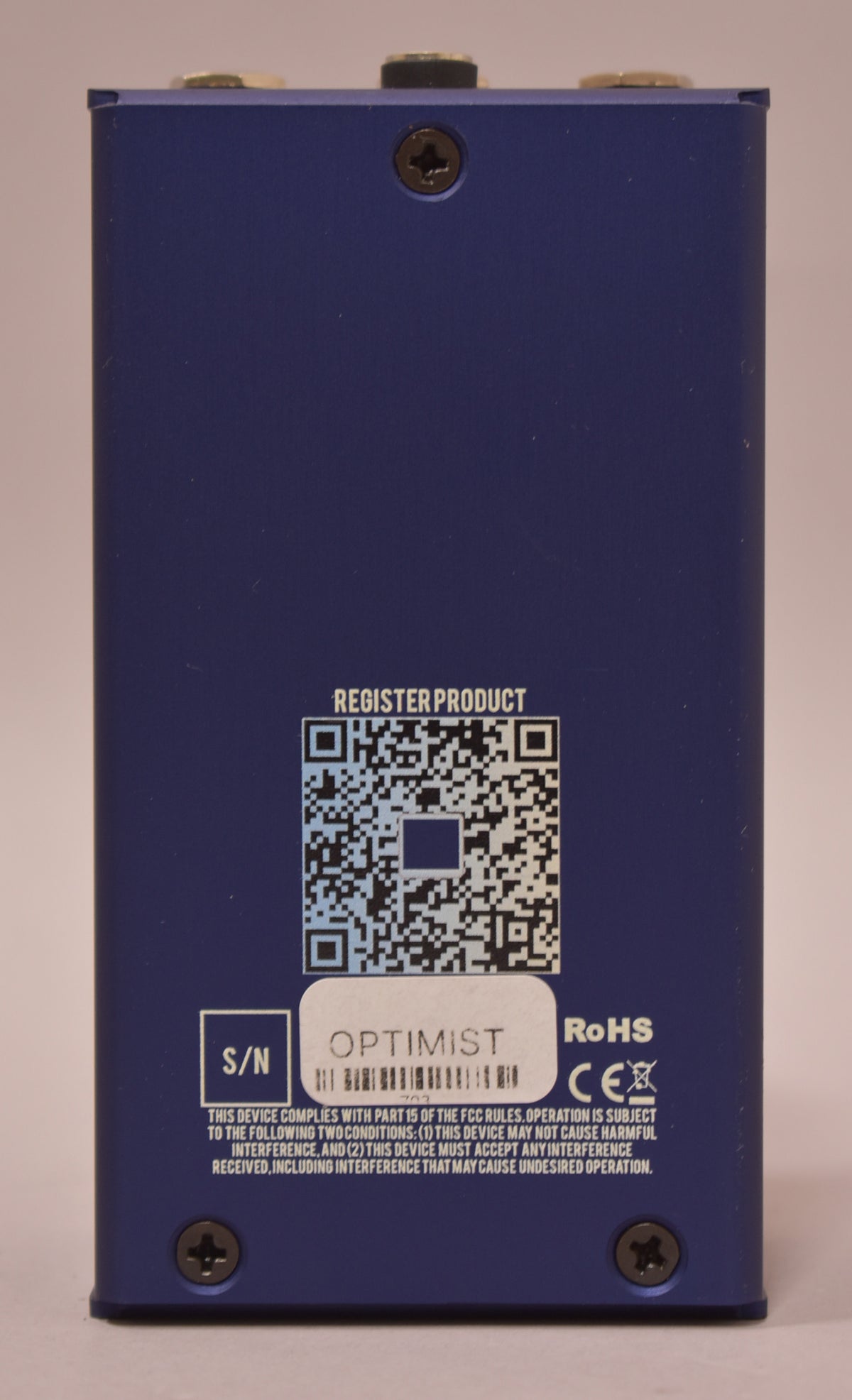 The dark blue pedal's back panel is shown, featuring a QR code, serial number, and product information in white text.