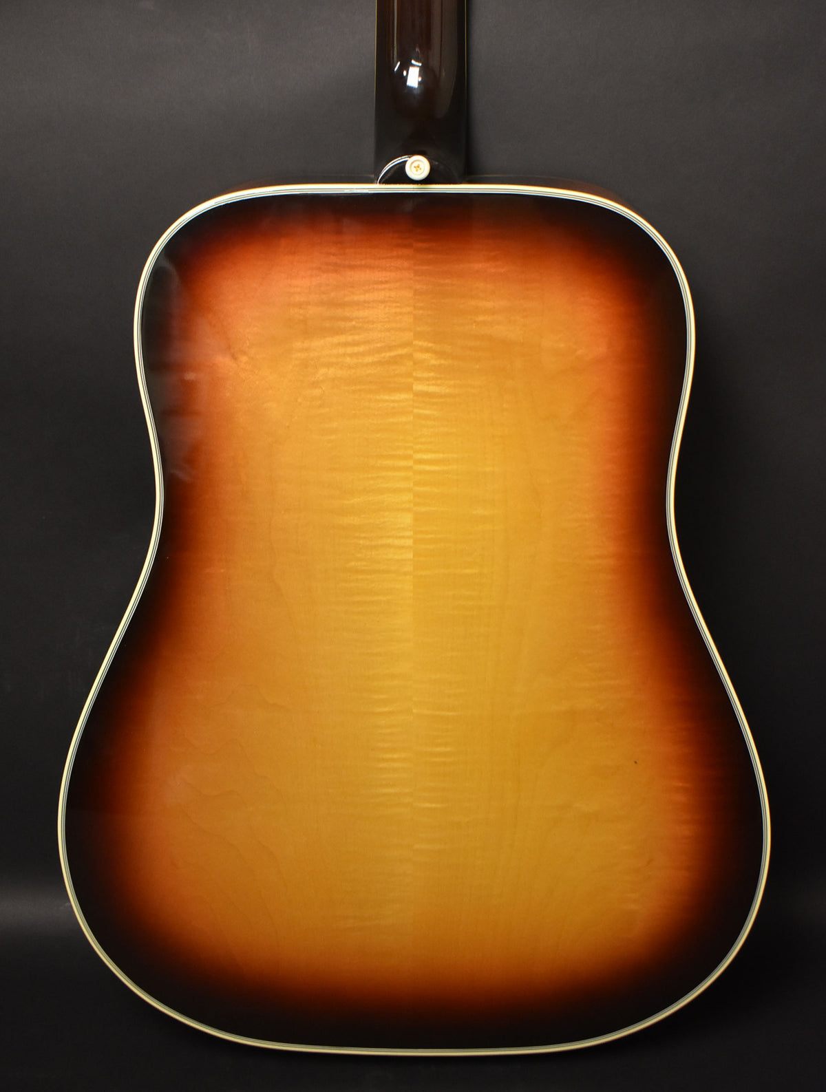 Full rear view of the acoustic guitar body, showing a sunburst finish with a flame maple grain and white binding.