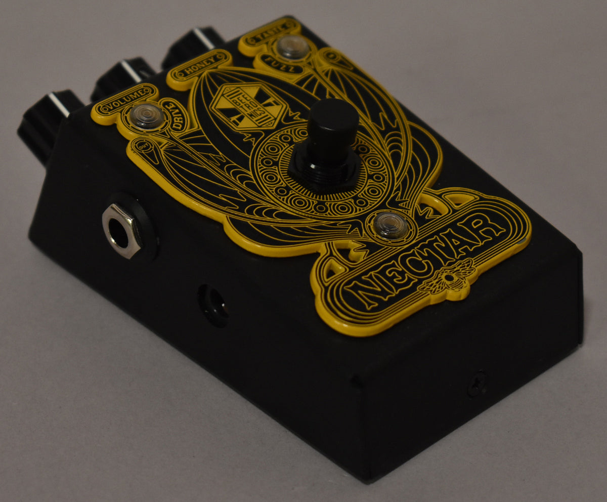 A black guitar pedal with a yellow, ornate "NECTAR" design, black knobs, and input jacks on the side.
