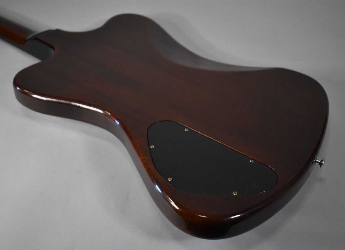 The back of a dark brown Firebird guitar, angled from the neck to the lower bout, showing a black control cavity cover.