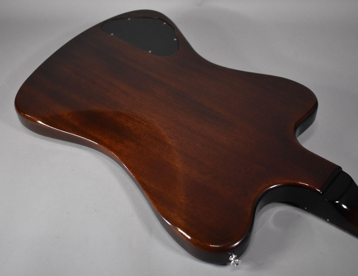 The back of a glossy, dark brown Firebird guitar, angled from the upper left, with a black control cavity cover.