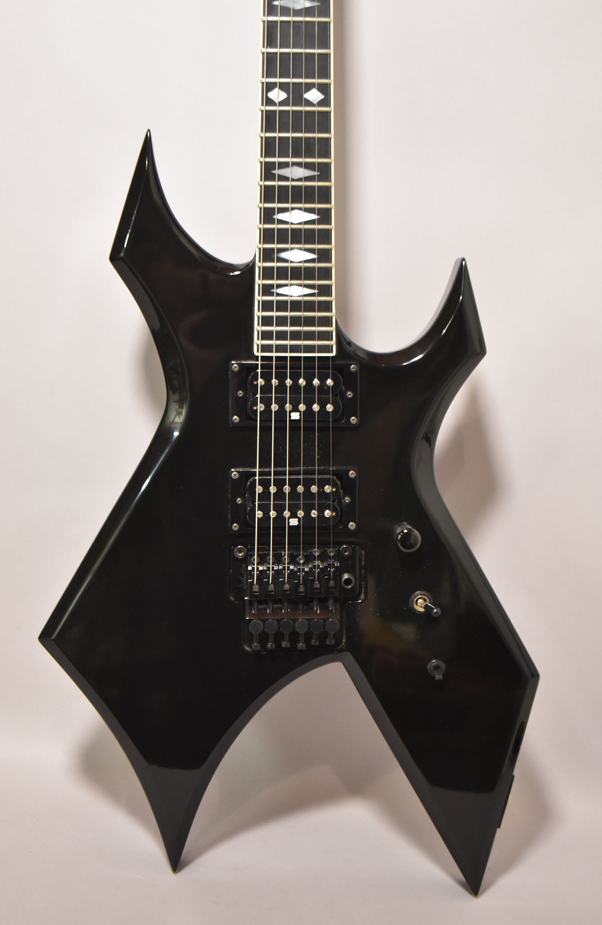Full view of the black Warlock Supreme, showing the body, two humbuckers, Floyd Rose bridge, and diamond fretboard inlays.