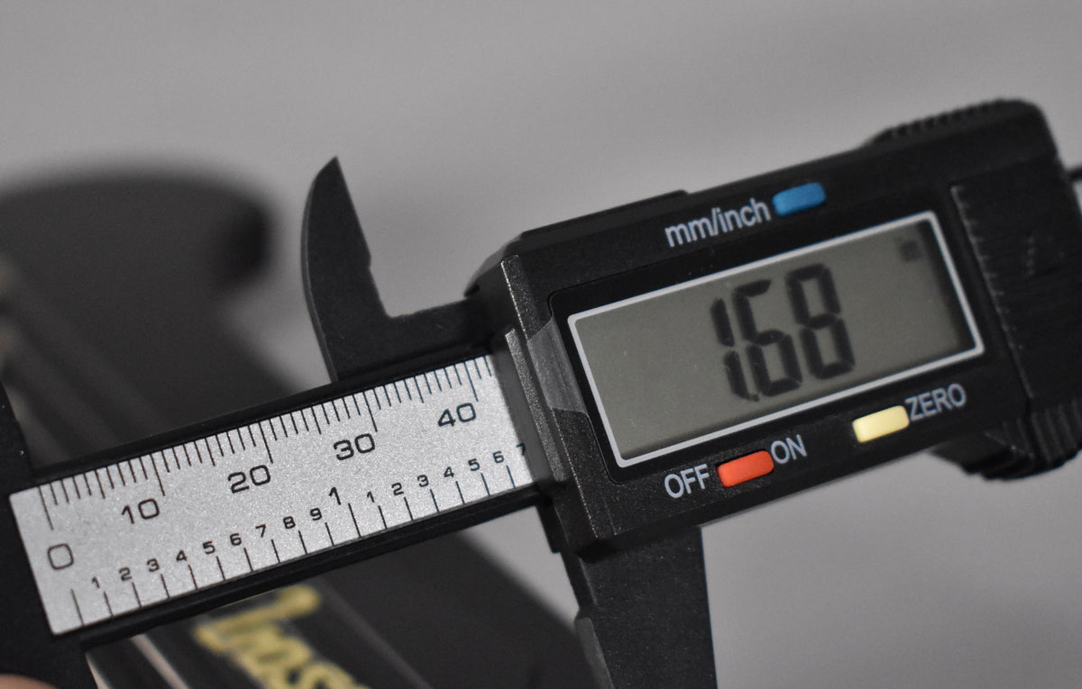 A digital caliper measures the nut width of the guitar neck, displaying "1.68" on its screen.