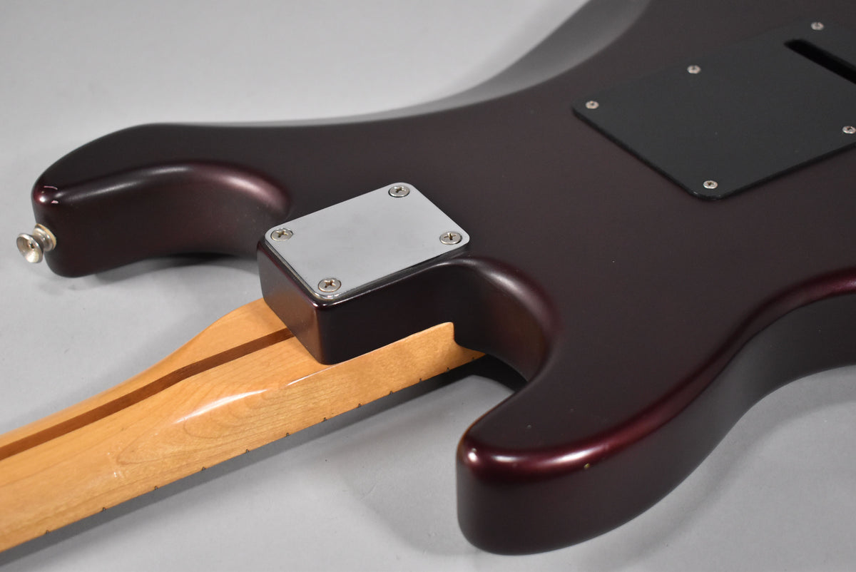 The guitar's satin metallic red body, with a chrome neck plate and black tremolo cover, meets a light maple neck.
