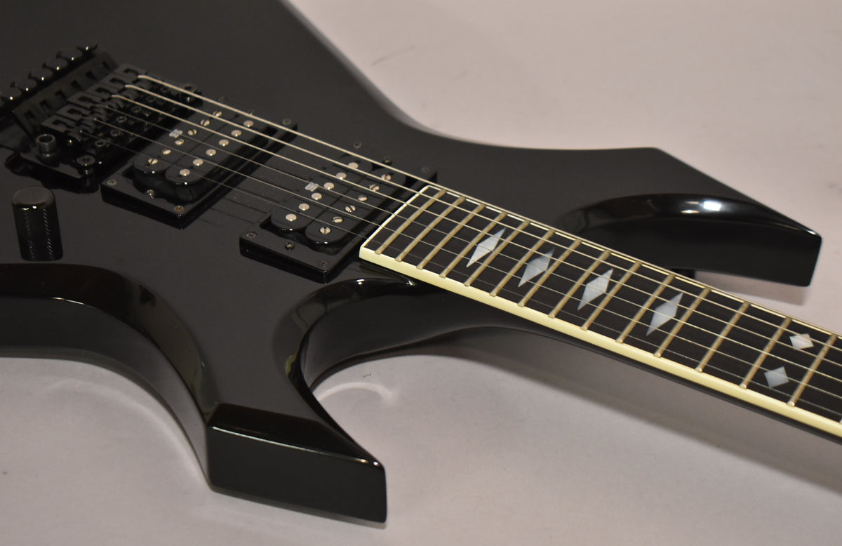Close-up of the glossy black body and fretboard with diamond inlays, showing two humbucker pickups and a single control knob.