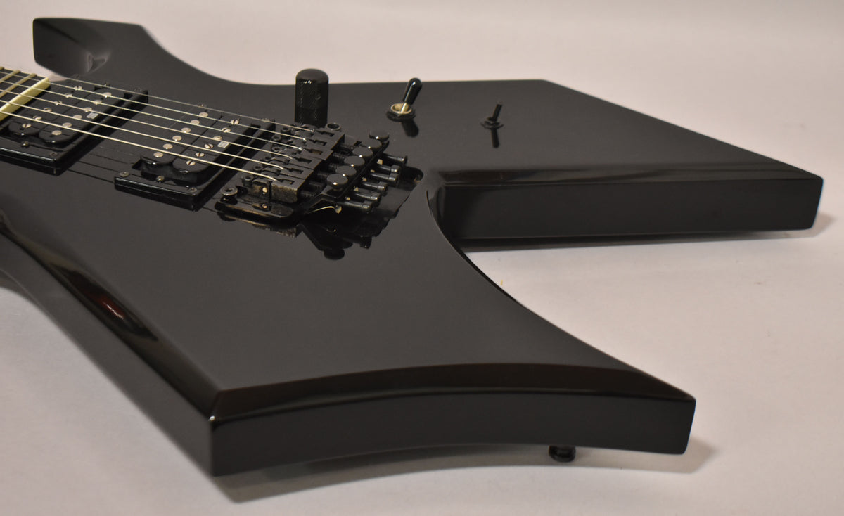 Close-up of the glossy black body, showing the bridge, two humbuckers, a volume knob, and a 3-way toggle switch.