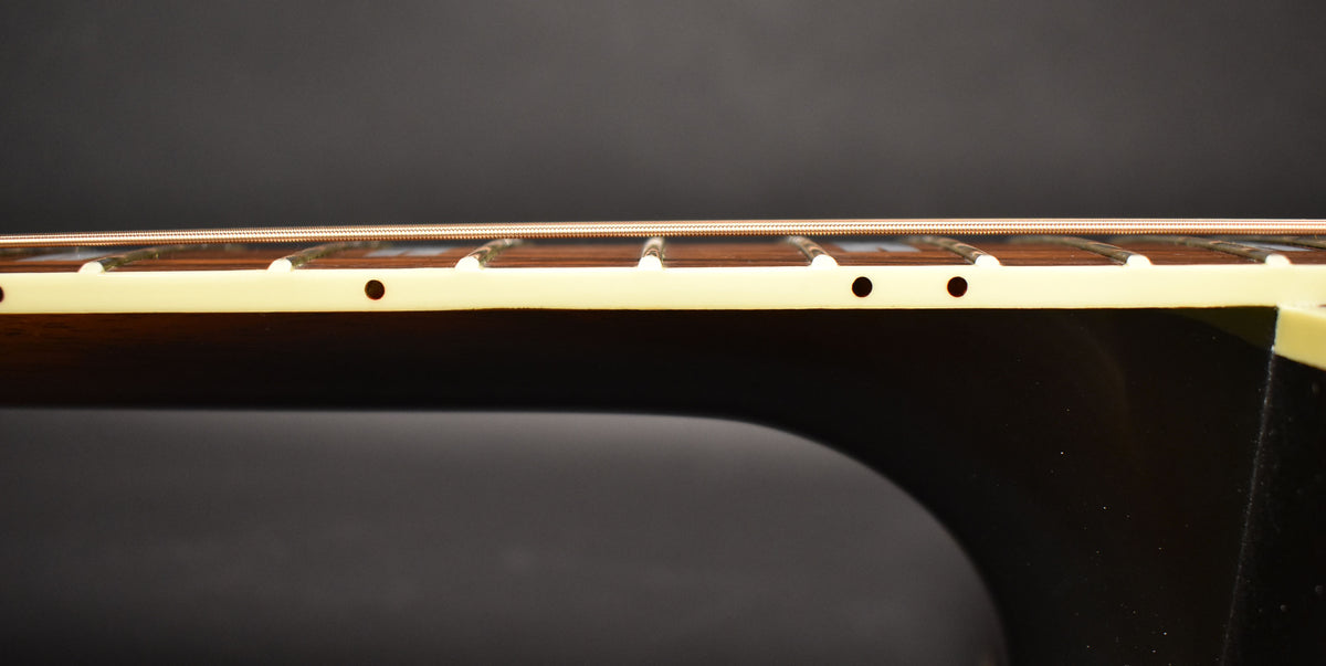 A close-up of the guitar's neck and fretboard from the side, showing the light-colored binding, dark fretboard, and side dot markers.