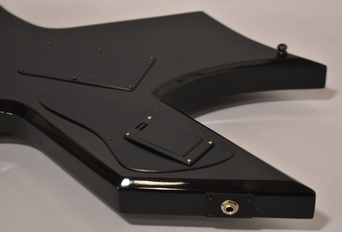 The guitar's glossy black body, viewed from the back, shows control cavity covers and an output jack on the lower horn.