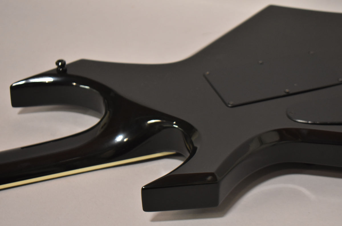 The guitar's black body, with a glossy finish on the neck and a matte finish on the back, shows a rear control cavity cover.