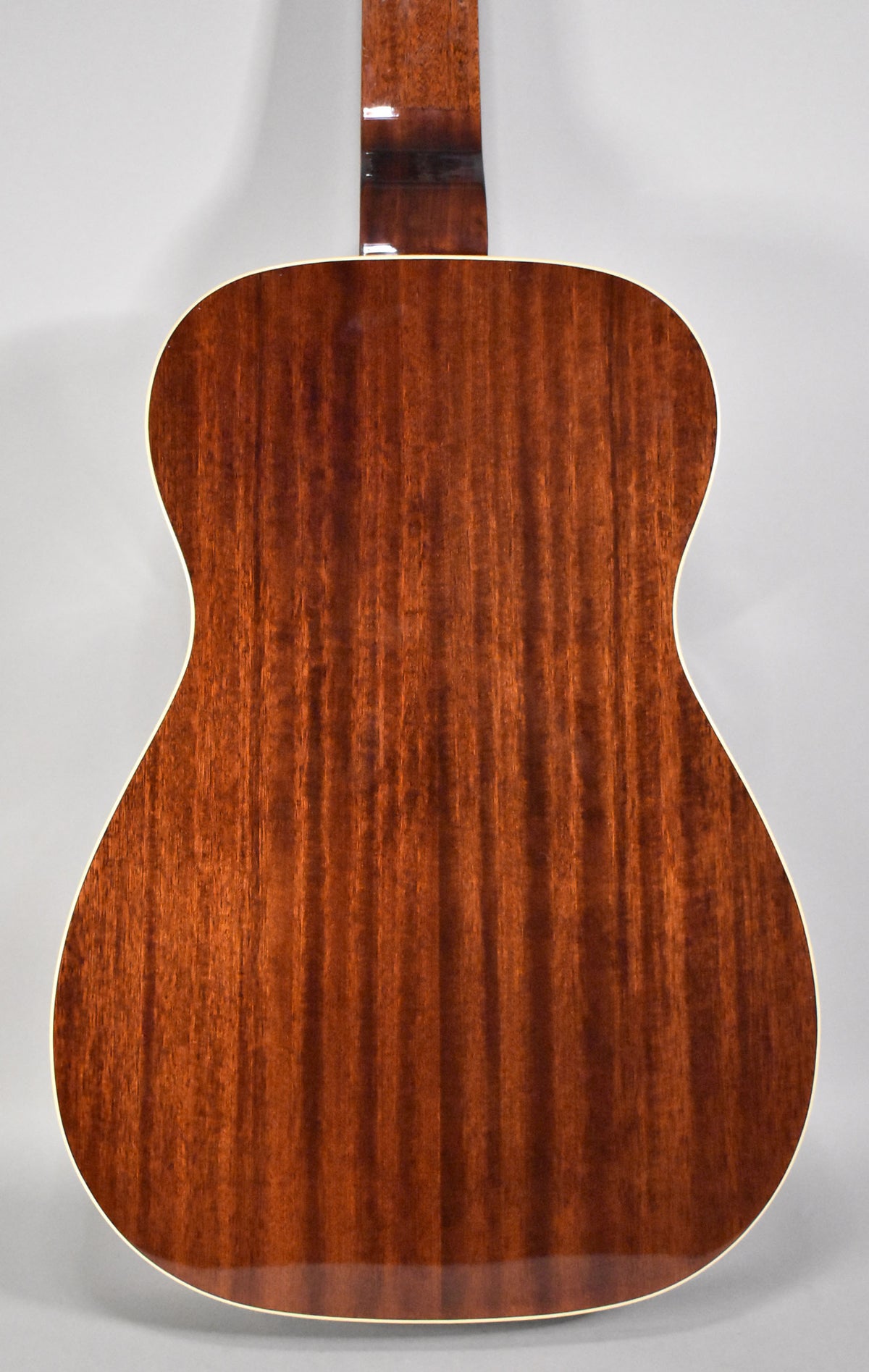 The back of the guitar, showing its dark reddish-brown wood grain with a glossy finish and light binding around the edges.