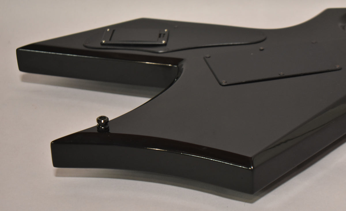 The guitar's glossy black body is angled, showing the back with two control cavity covers and a strap button.