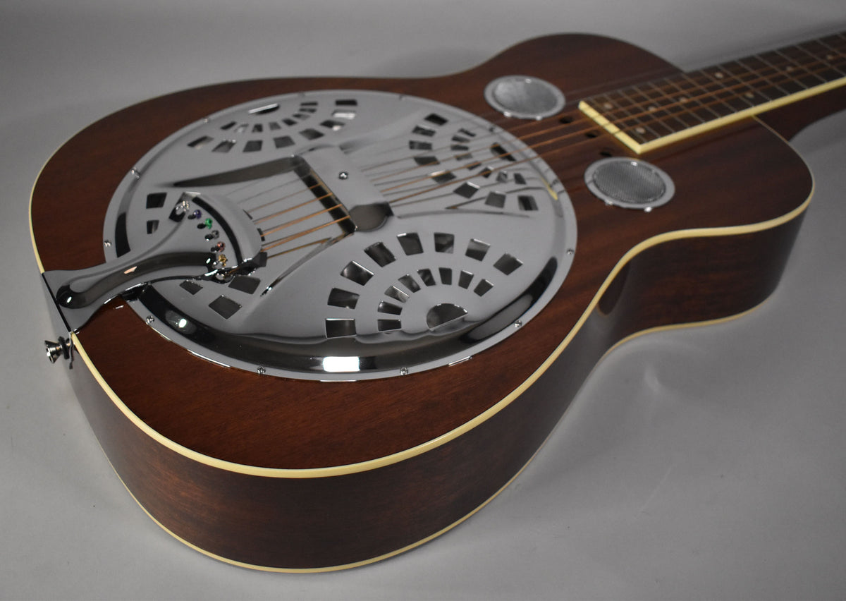 The left-handed resonator guitar's dark brown body with cream binding is angled, showing its chrome cover plate and tailpiece.