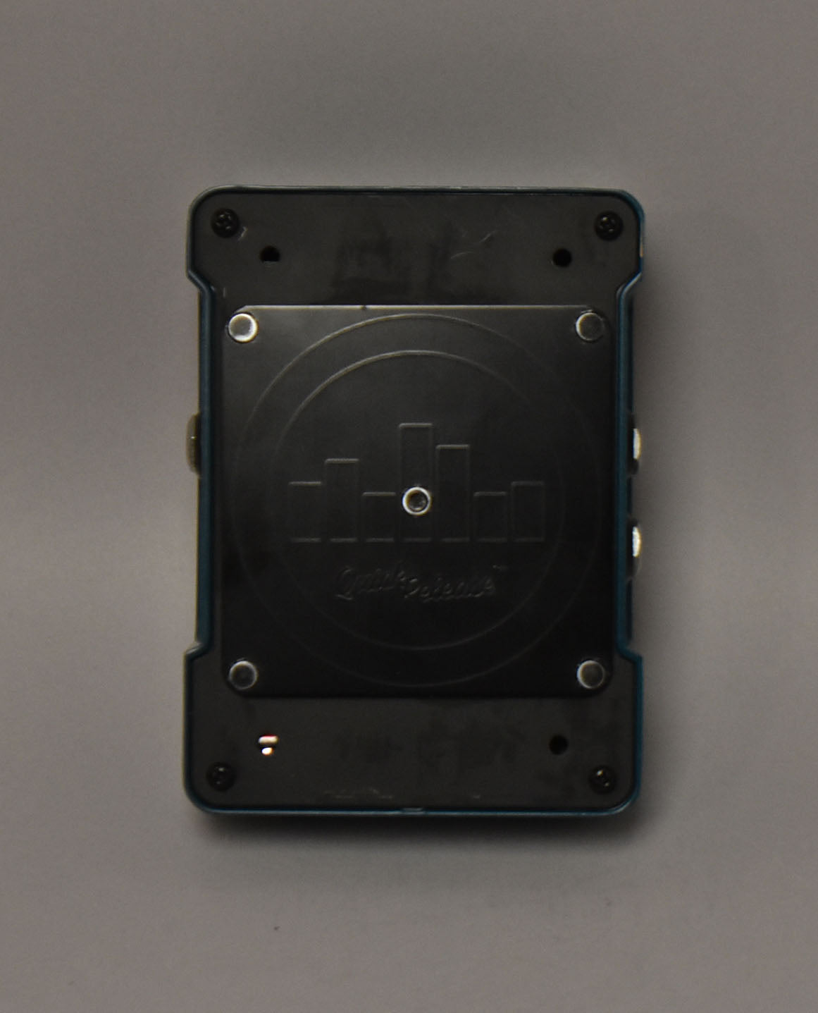 The pedal's dark blue underside is shown, with a black metal plate secured by four silver screws and a small orange LED.