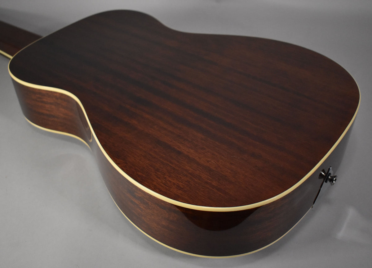 The dark brown, glossy back of the resonator guitar is angled, showing the cream binding along the edges and a strap button.