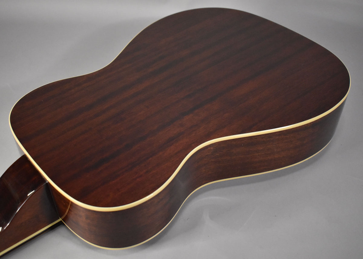 The back of the resonator guitar, showing its dark brown wood grain, natural gloss finish, and cream binding along the edges.