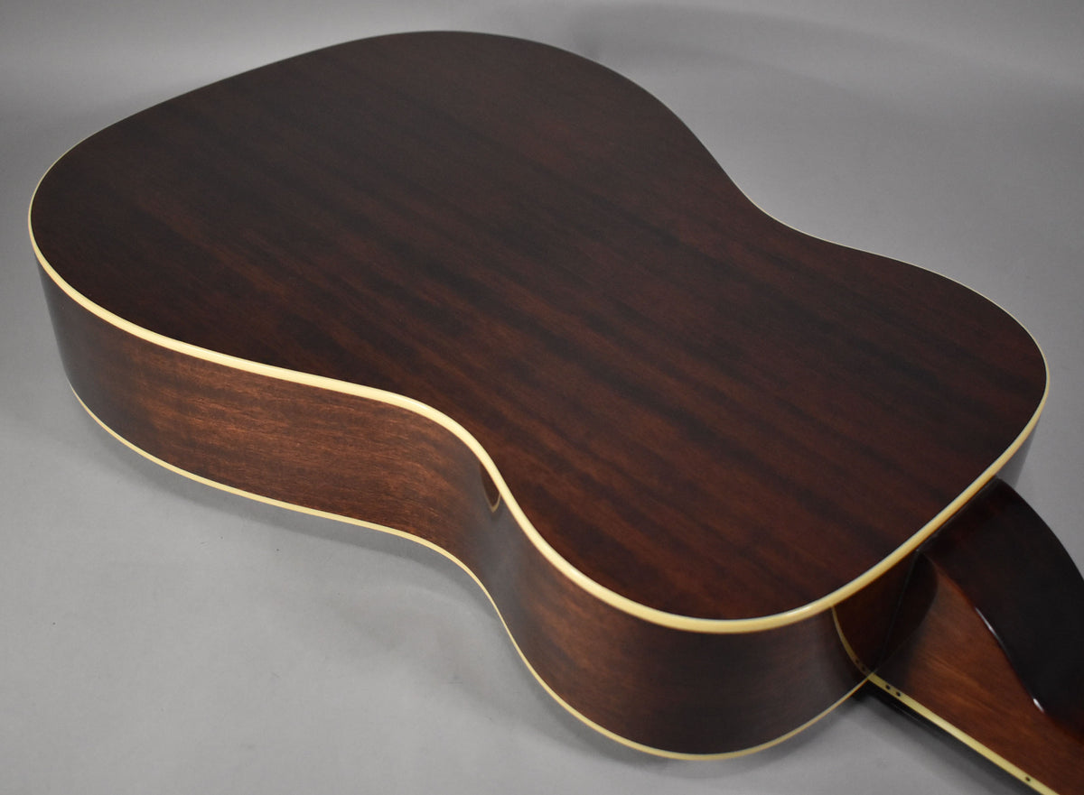 The back and side of the dark brown resonator guitar are shown, featuring a natural wood grain and cream binding along the edges.