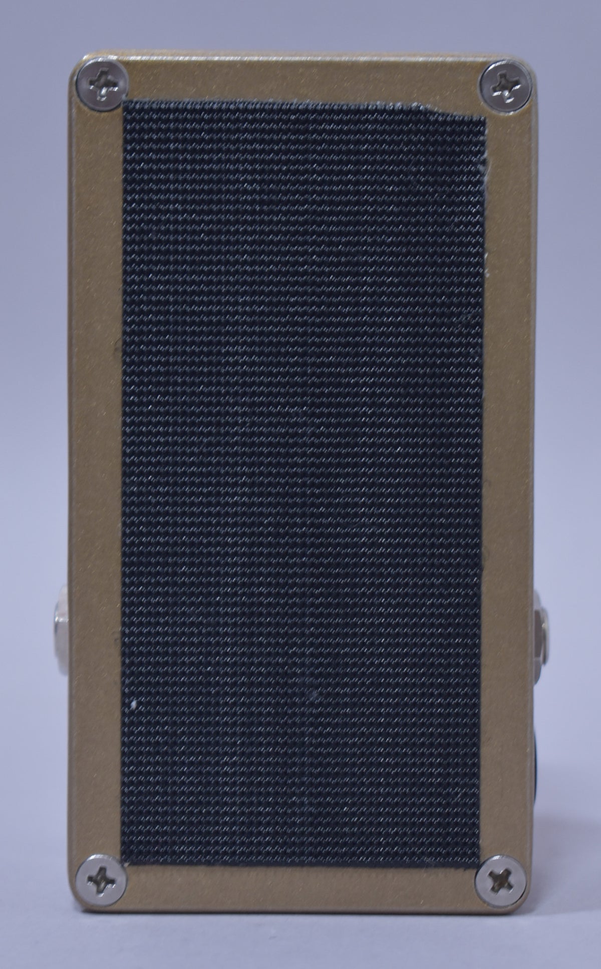 The pedal's bottom is tan with a large black textured grip pad, secured by four silver Phillips head screws.