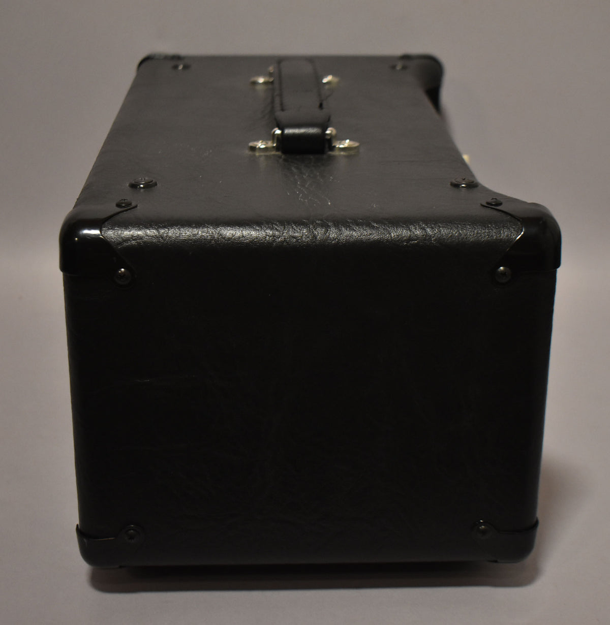 The black amplifier head is viewed from the right side, showing the textured tolex, metal corner protectors, and top handle.
