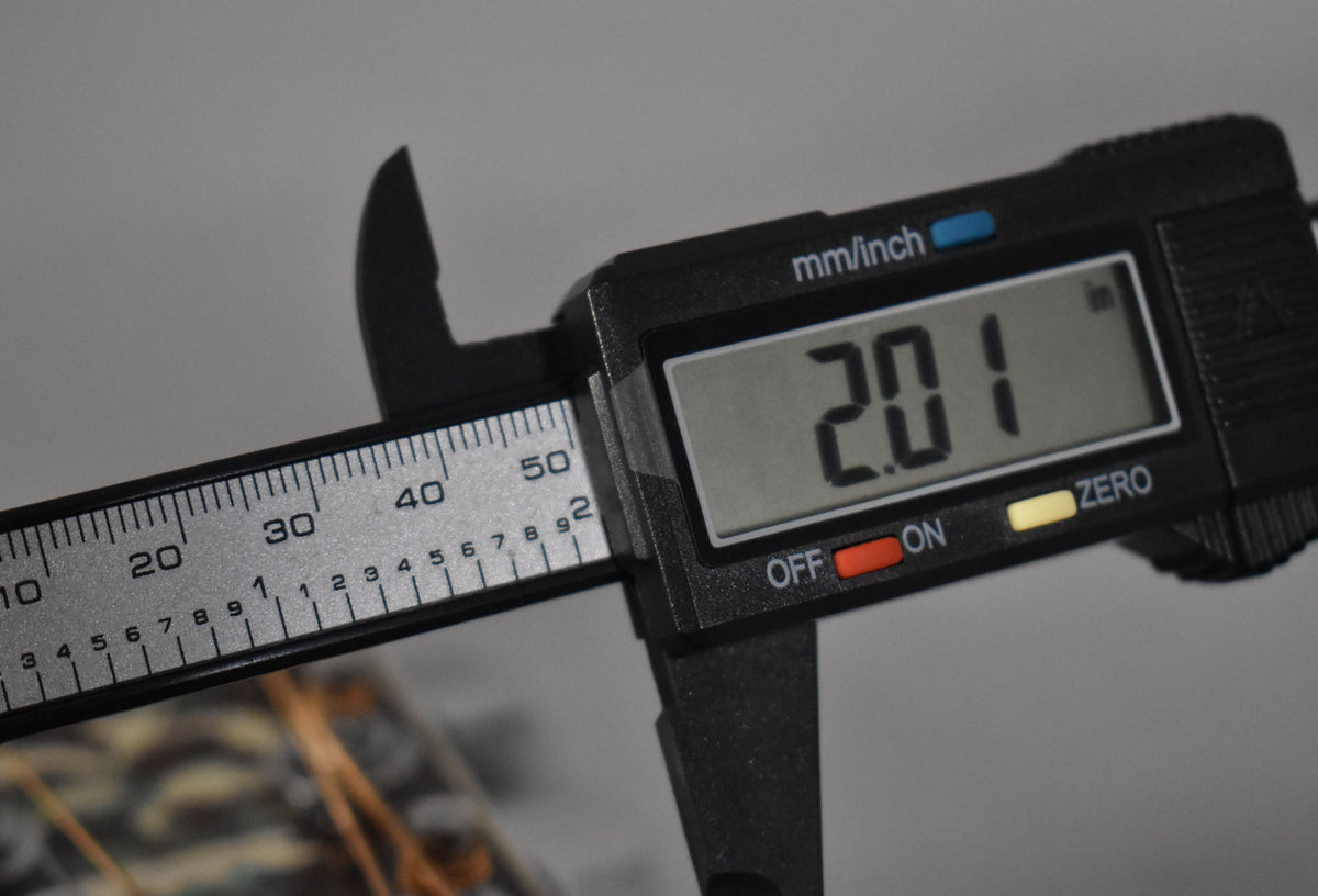 A digital caliper measures the nut width at 2.01 inches, with the top of the dark wood fretboard visible below.