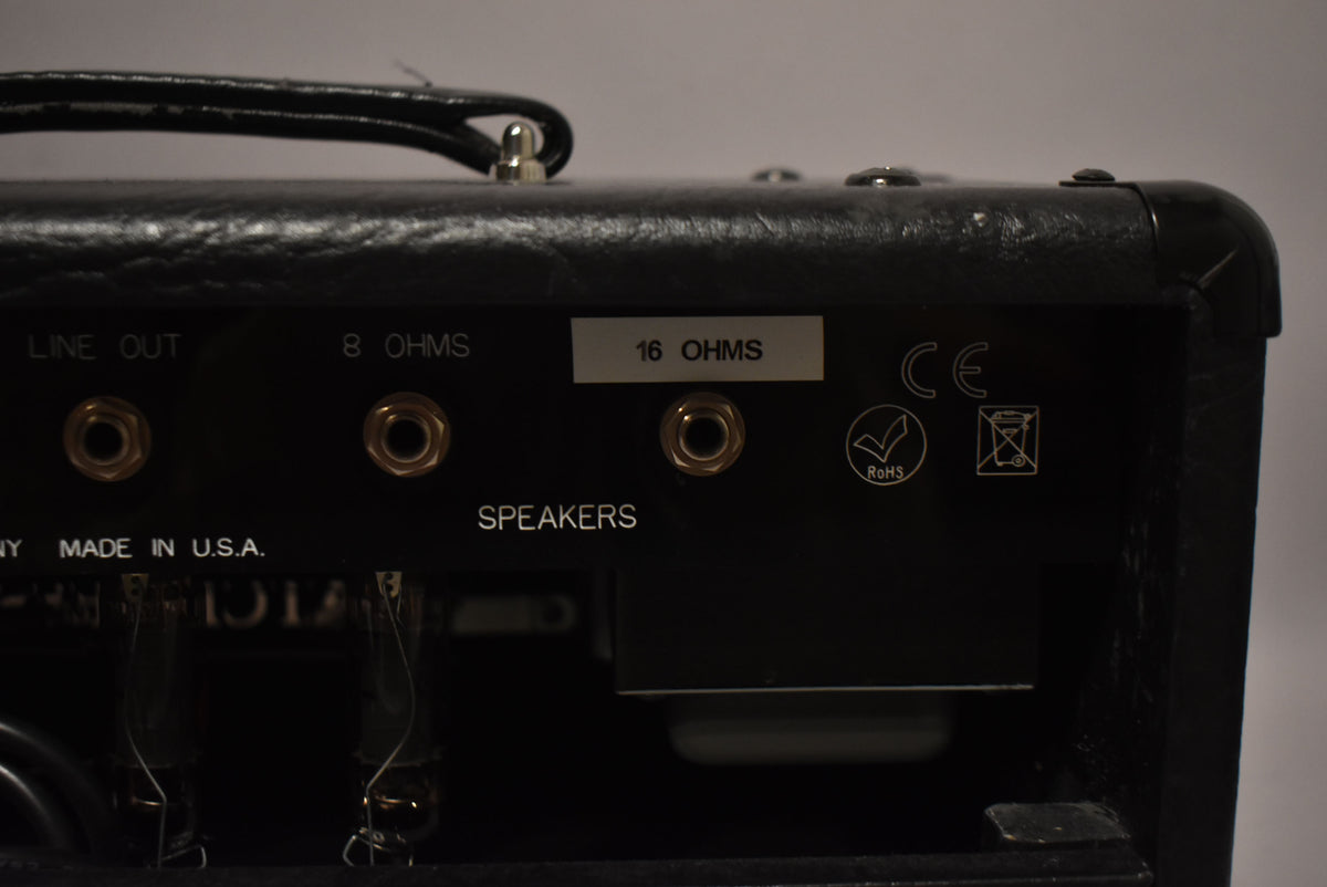 Rear view of the black amplifier head, showing the speaker outputs for 8 and 16 ohms, a "Line Out" jack, and two visible vacuum tubes.