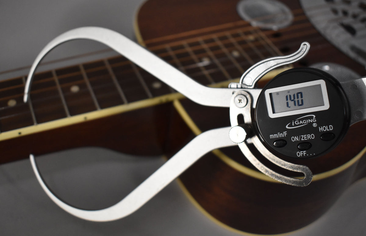 A digital caliper measures the string height at 1.40mm above the dark fretboard of the natural gloss resonator guitar.