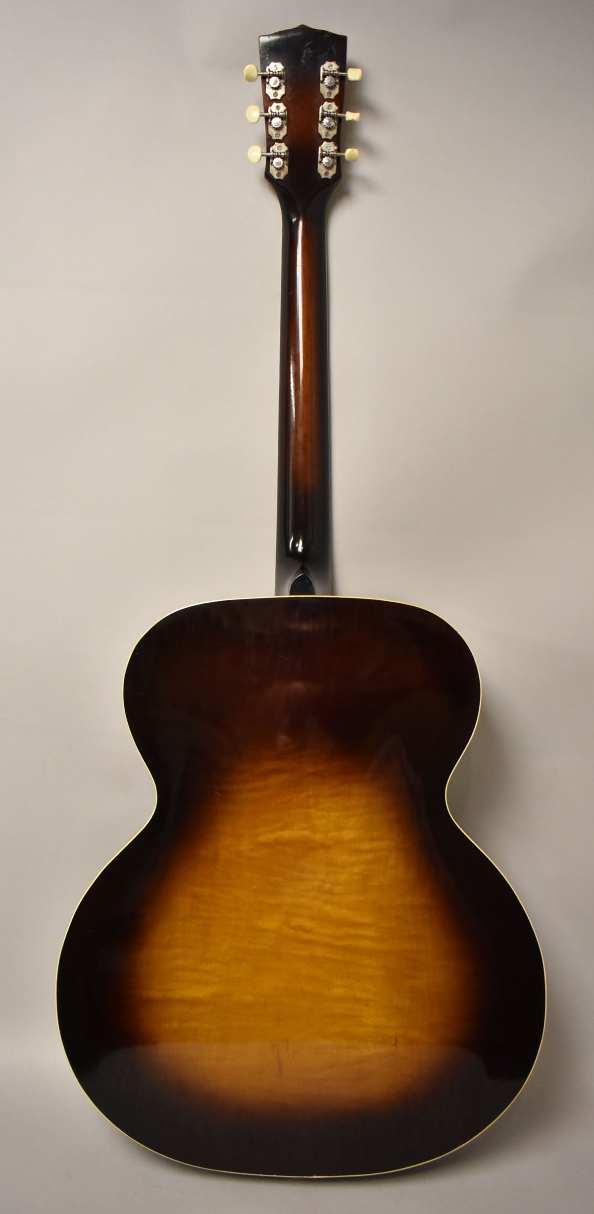 Full rear view of the sunburst archtop acoustic guitar, showing the dark brown headstock with six cream tuners and the flame maple back.