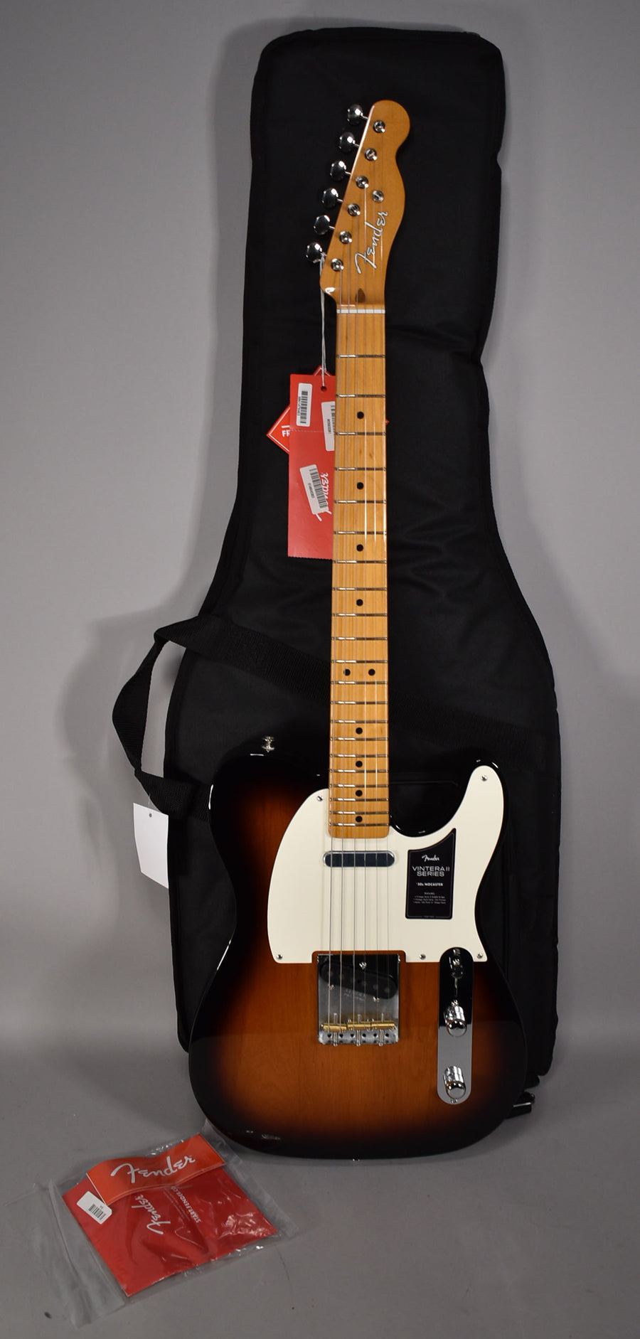 Full view of a 2-Color Sunburst Nocaster with a maple neck, white pickguard, chrome hardware, and a black gig bag behind it.