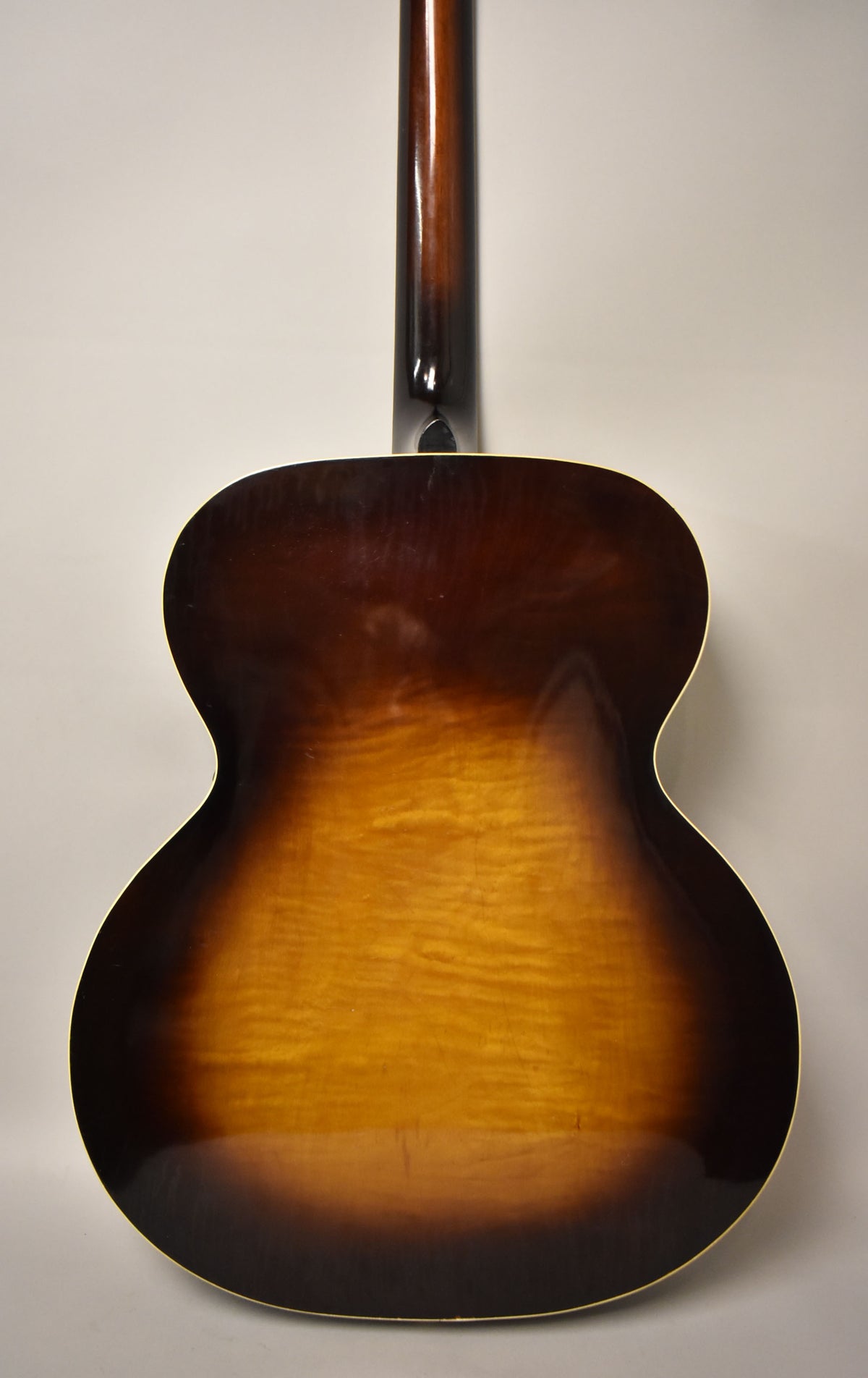 The guitar's sunburst back shows a dark brown top and bottom fading to a wavy amber center, with light wear and binding.