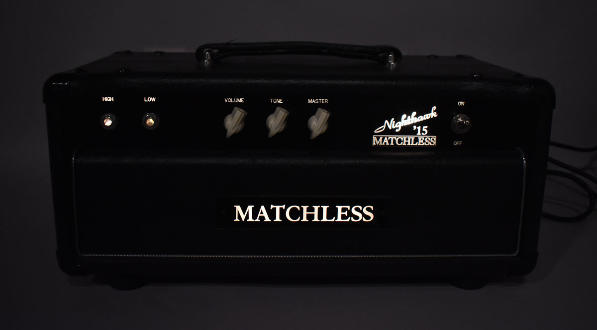 Front view of a black tube amp head with a leather handle, three cream chicken-head knobs, and two glowing input lights.