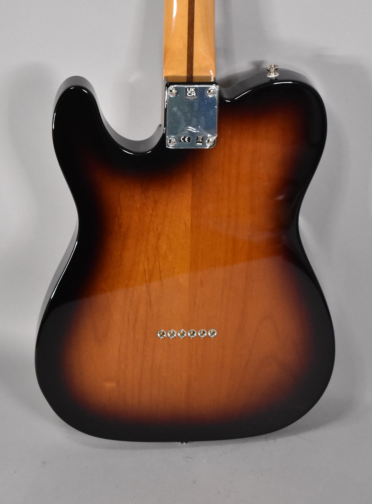 The guitar's back, in 2-Color Sunburst, shows a chrome neck plate, a strap button, and six string-through-body ferrules.