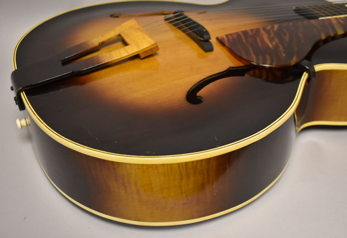 Close-up of the guitar's lower bout, showing the sunburst finish, f-hole, tortoise pickguard, and a cream binding with some wear.