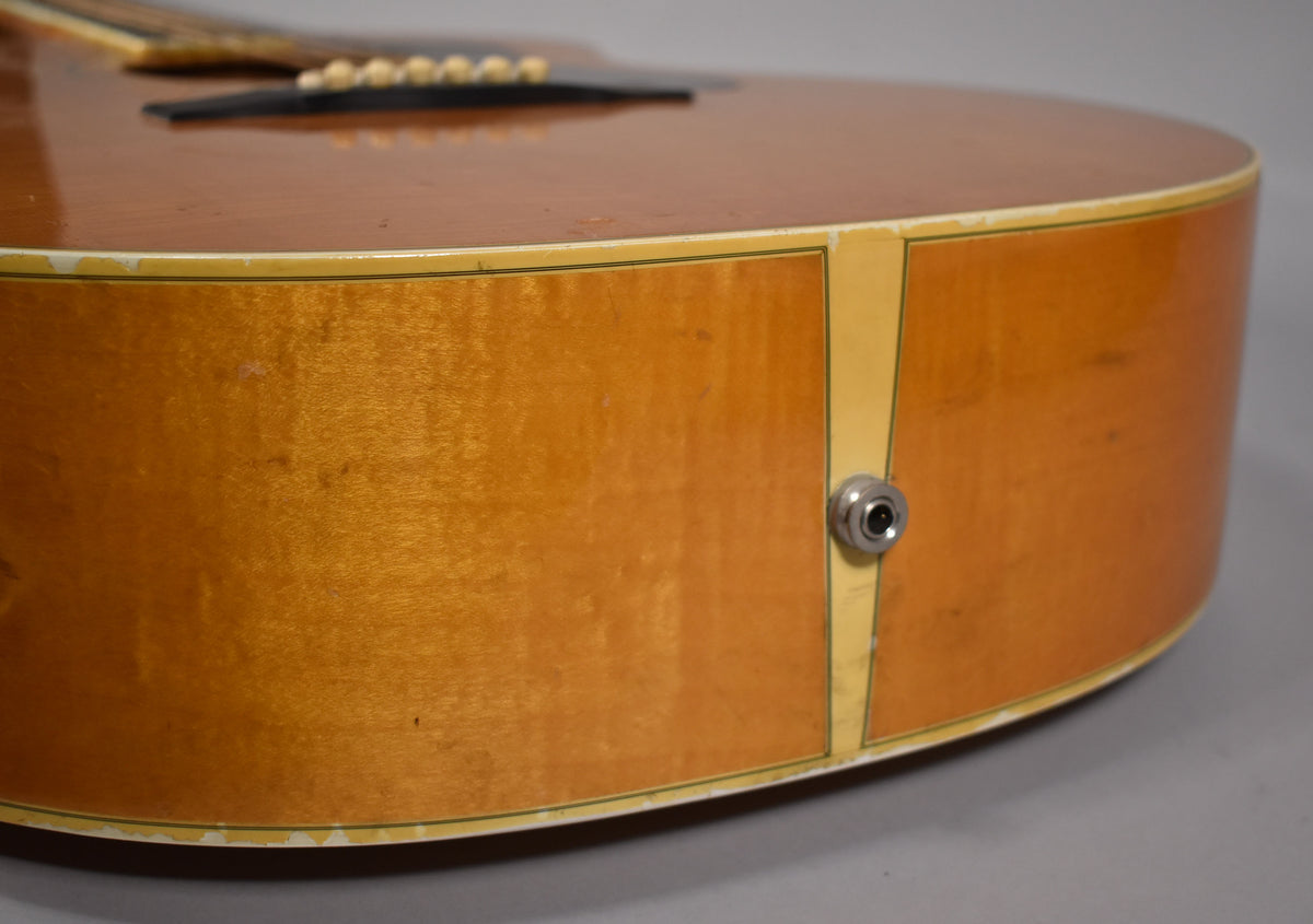 Close-up of the guitar's lower bout, showing the natural blonde finish, white binding wear, and a chrome output jack.