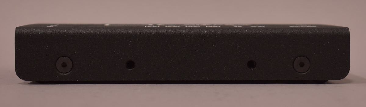 The black textured power supply is viewed from the side, showing two hex screws and two small holes along its length.
