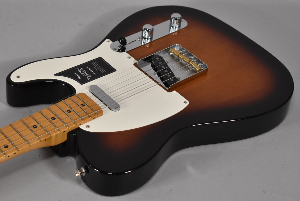 The Nocaster's glossy 2-color sunburst body, white pickguard, and maple neck are viewed from above, angled from the lower left.
