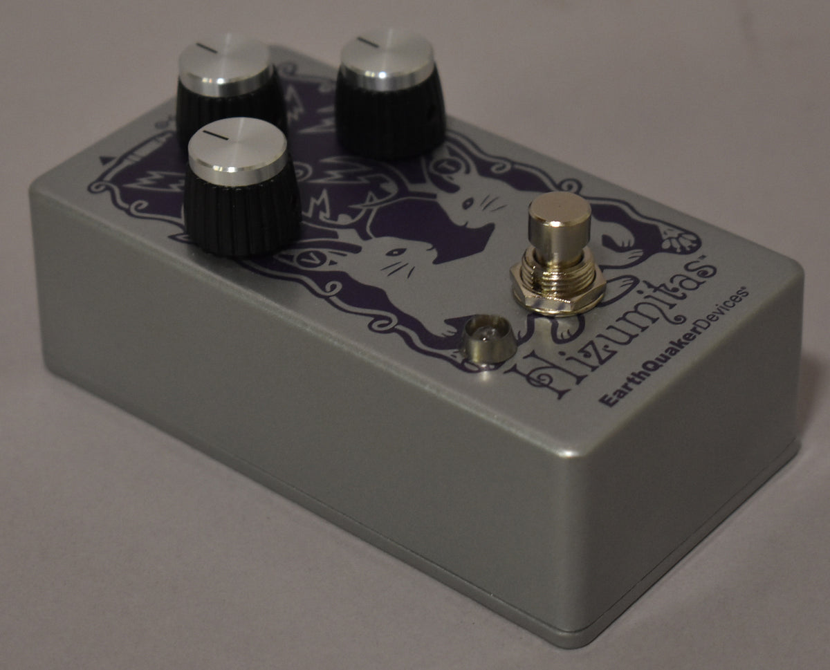 A silver-grey pedal with three black ridged knobs with silver tops, a silver footswitch, and a purple cat graphic.