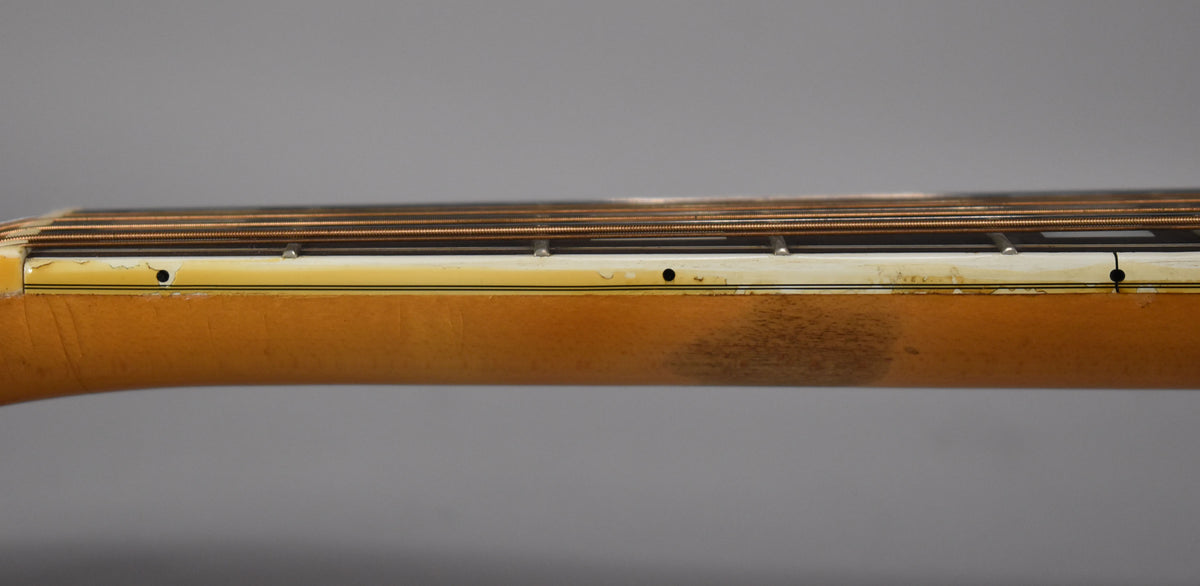 The guitar's neck, with a blonde finish, shows dark wear on the back and chipped binding along the fretboard edge.